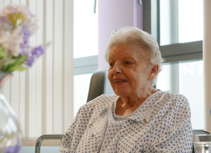 Senior woman on bed by window at hospital