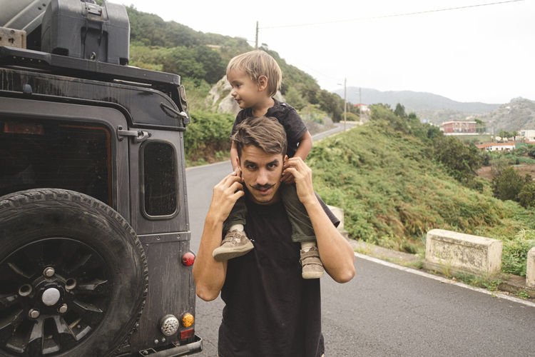 A man carries a child on his should in the countryside