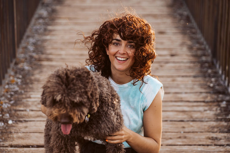Portrait of woman embracing dog on boardwalk