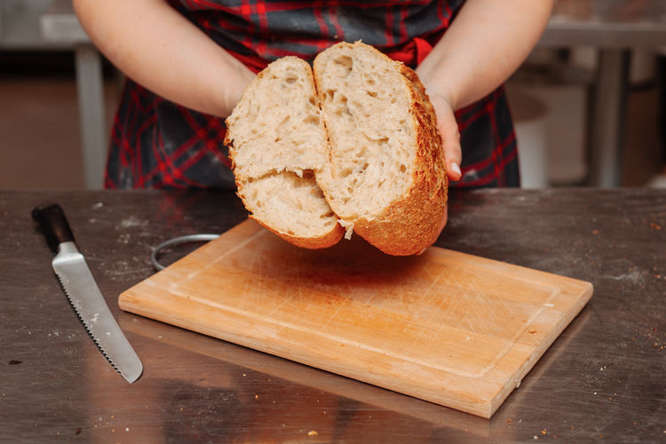 Midsection of woman holding bread on cutting board