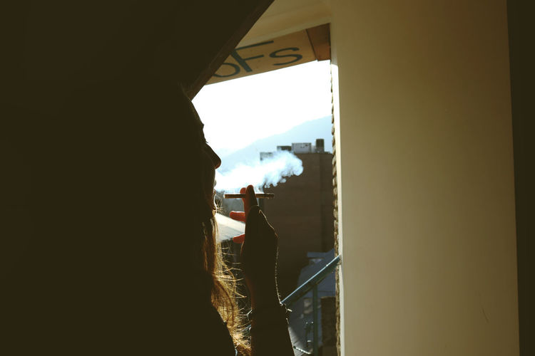 Rear view of silhouette woman against sky seen through window