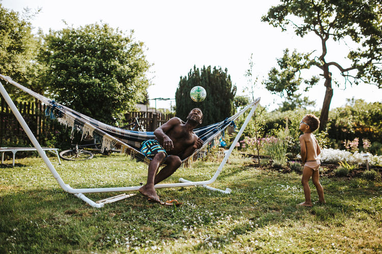 black father and son playing with ball outdoors Family Fatherhood Moments Shirtless Ball Boy Boys Child Day Emotion Enjoyment Father Father & Son Fun Grass Group Of People Hammock Leisure Activity Lifestyles Nature Outdoors People Playing Positive Emotion Soccer Tree Summer Road Tripping My Best Photo Moms & Dads