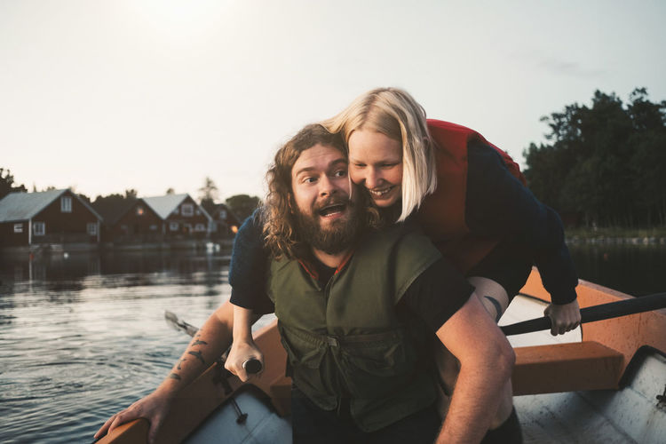 Happy couple enjoying in boat on lake against sky