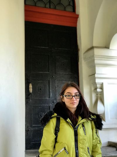 Portrait of young woman wearing warm clothing standing against door