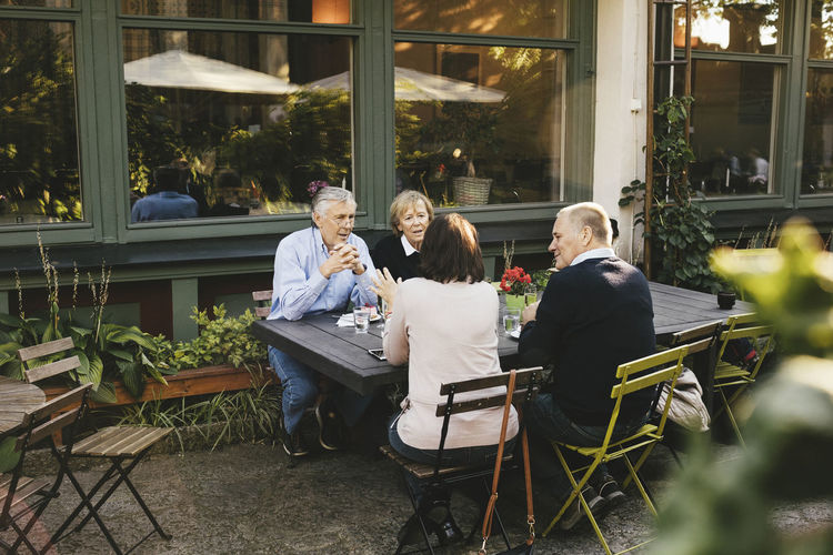 Senior male and female friends having talking at outdoor restaurant