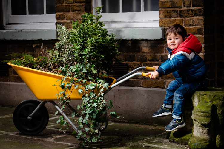Full length of boy holding plant in yard