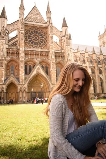 Happy woman sitting against westminster abbey