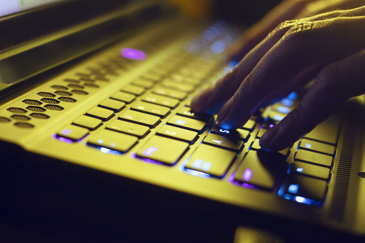 Close-up of hand using illuminated computer keyboard