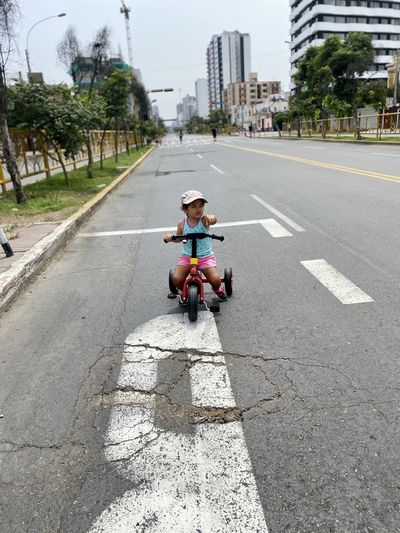 Girl riding bicycle on road in city