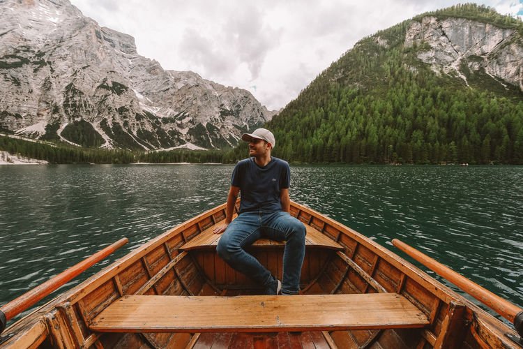 Man sitting by lake against mountains
