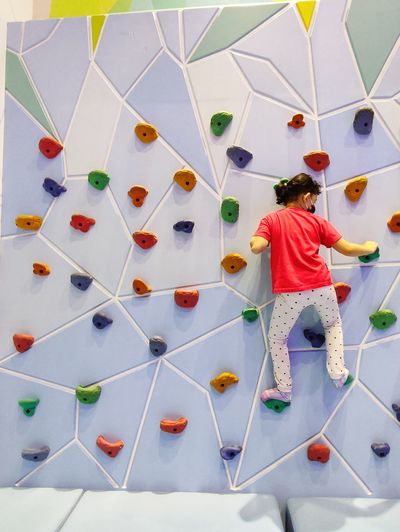 Rear view of girl climbing on wall