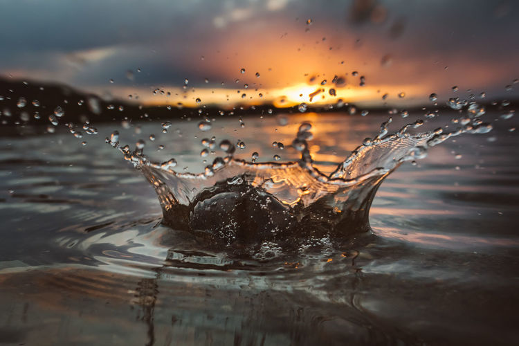 Close-up of water splashing against sky during sunset