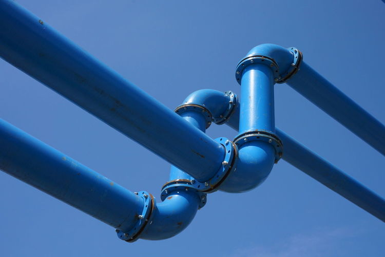 Low angle view of blue pipelines against clear blue sky