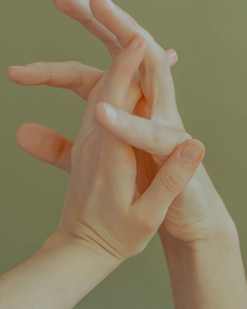 Close-up of hand holding hands over white background
