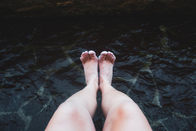Female legs and feet getting wet in the river against river water
