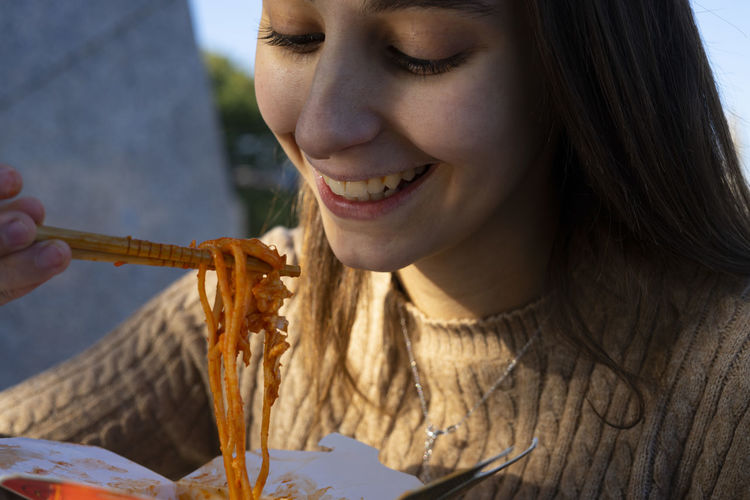 Close-up portrait of a smiling young woman eating food