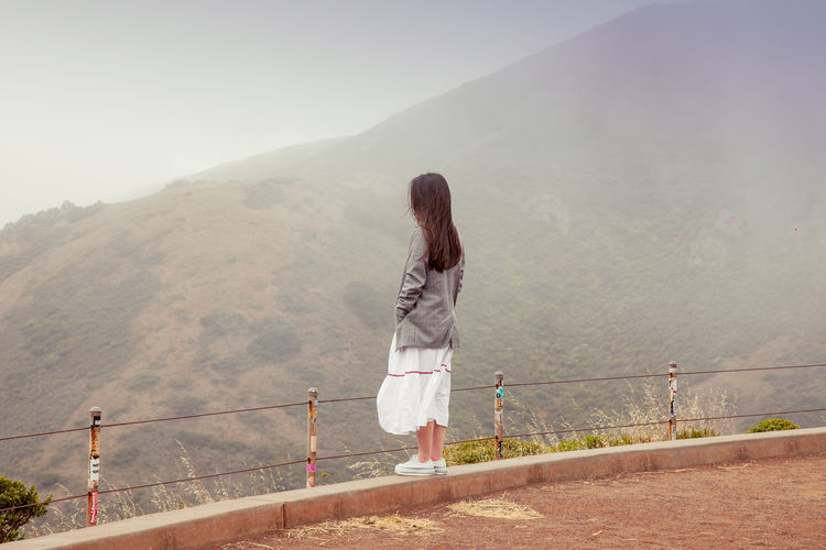 Stylish tourist girl admires wonderful landscape. woman admire mountains from observation desk.