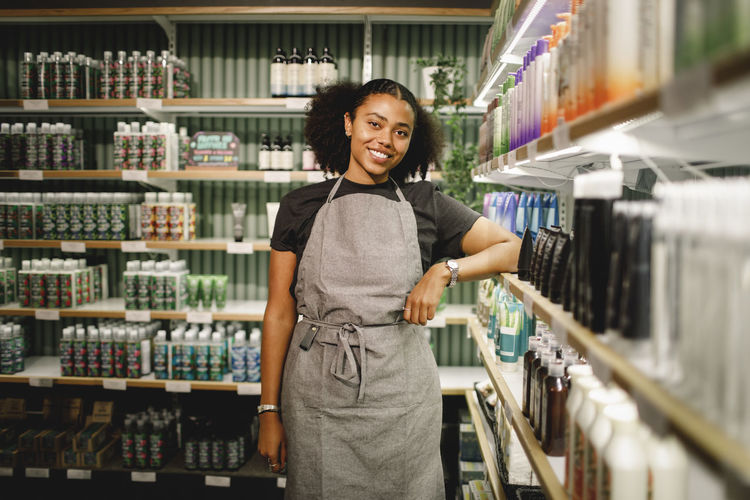 Portrait of smiling saleswoman standing in supermarket
