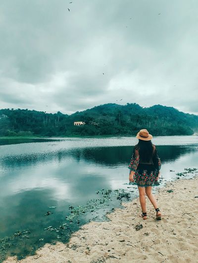 Full length of woman standing on shore against sky