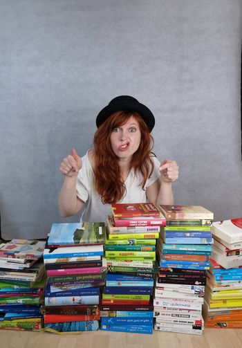 Portrait of young woman sitting on stack of books