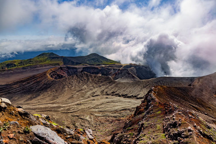 Heavy smoke bursting out from active volcano crater of aso in the volcanic landscape