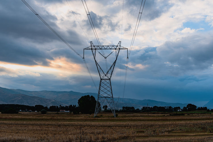 Electricity pylon on field against sky