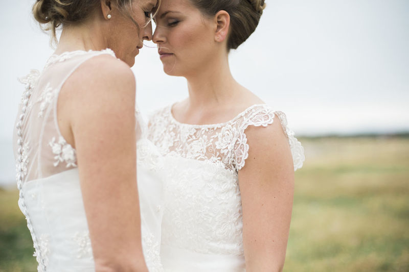 MIDSECTION OF MOTHER AND DAUGHTER STANDING ON FIELD