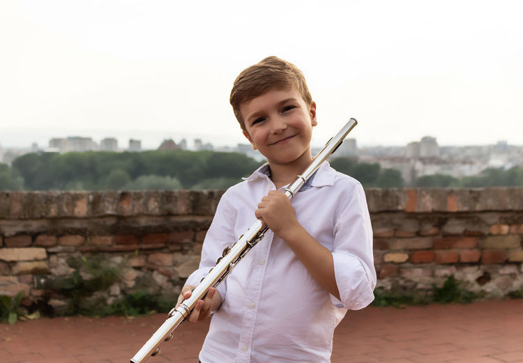 Portrait of cute little flautist outdoors.