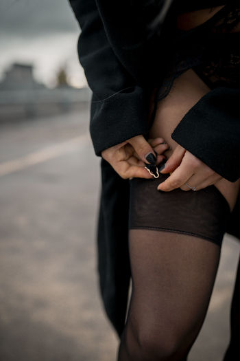 Midsection of woman holding sock standing on street