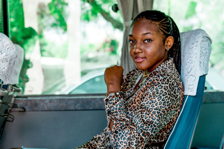 A happy young woman sitting in a bus looking at camera