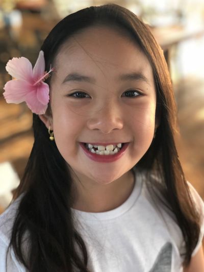 Close-up portrait of smiling girl wearing flower