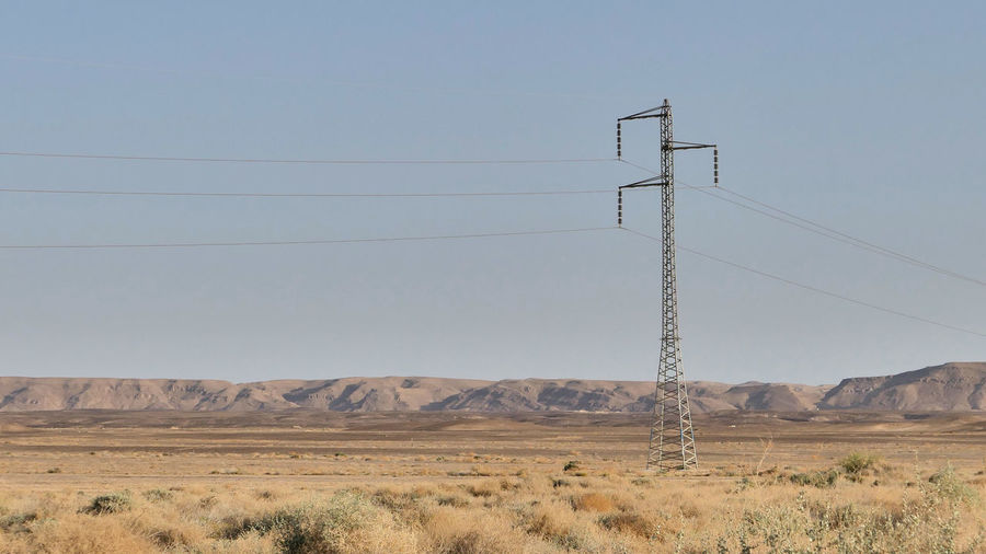 Electricity pylon on desert against clear sky