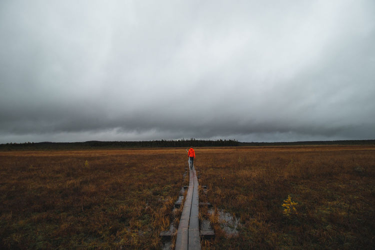 Woman wearing red jacket walks along a wooden walkway in the area around rovaniemi, lapland, finland