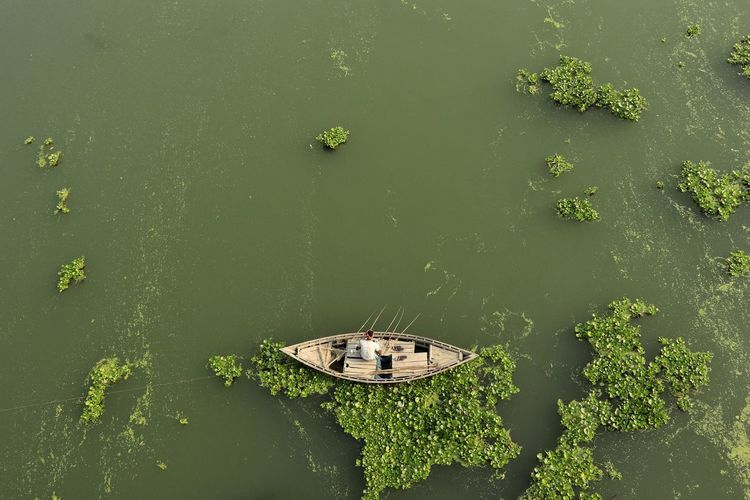 High angle view of boat floating on river and fishing by fishing rod