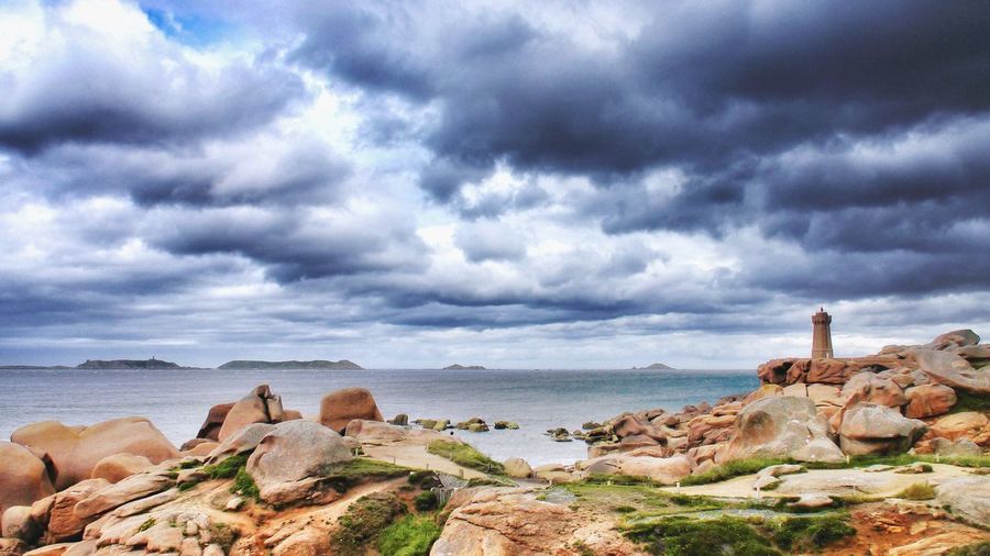 Scenic view of rocky beach against cloudy sky