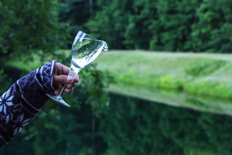 Cropped image of hand holding drinking water in glass