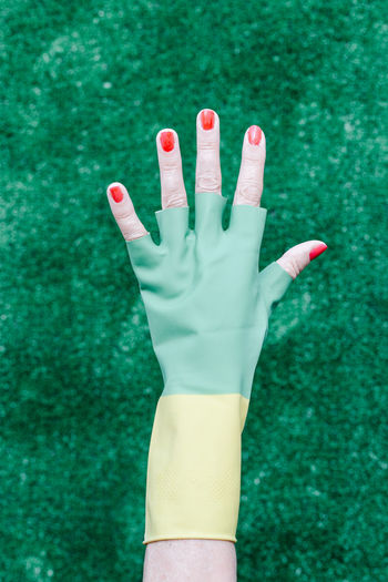Elderly hand with broken rubber gloves showing red painted nails