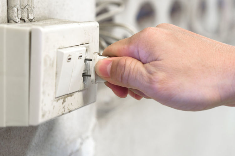 Close-up of person hand pressing plug in electrical outlet