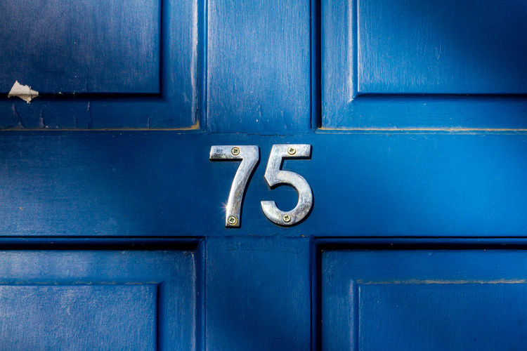 House number 75 on a blue wooden front door in london 