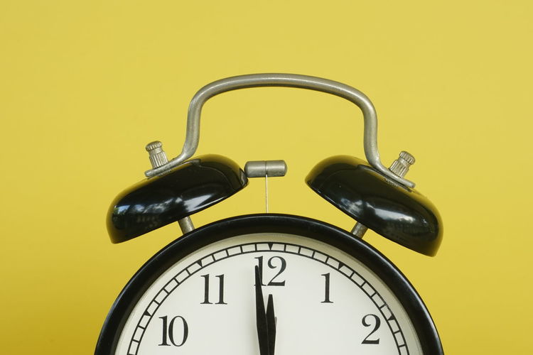Close-up of clock on yellow background