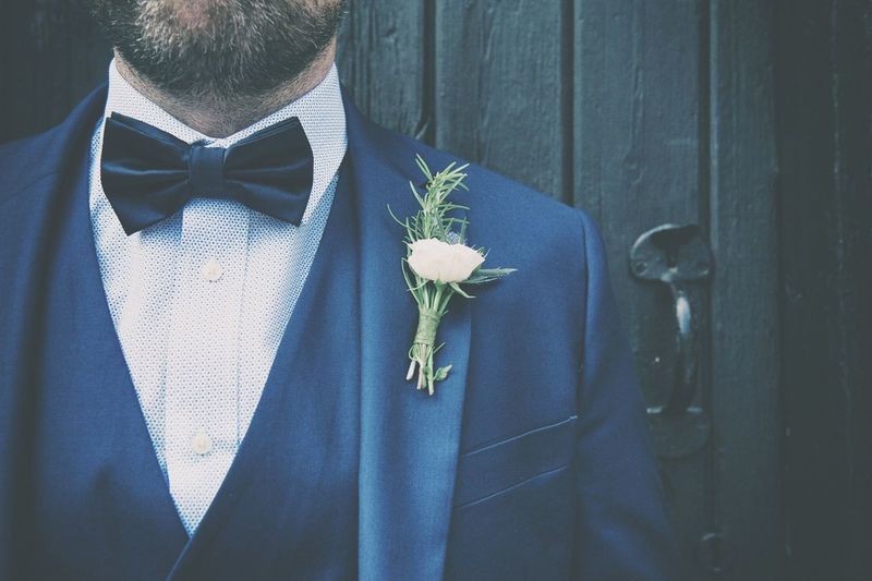 Midsection of bridegroom wearing suit with boutonniere
