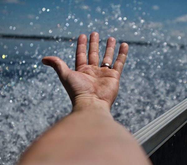 Cropped image of man hand gesturing at beach