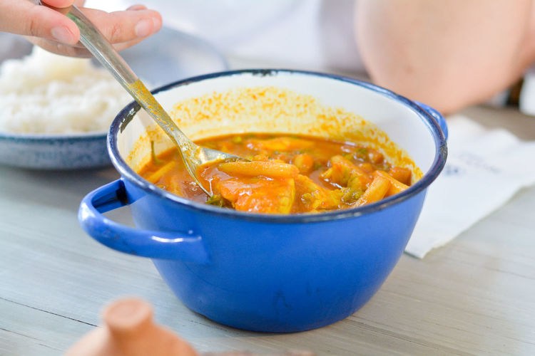 Midsection of person holding soup in bowl on table