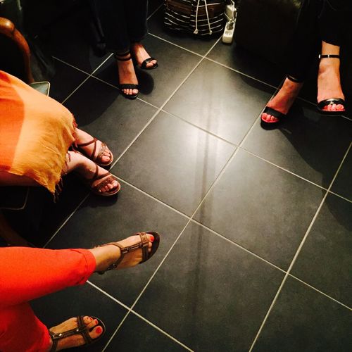 Low section of women sitting on black tiled floor
