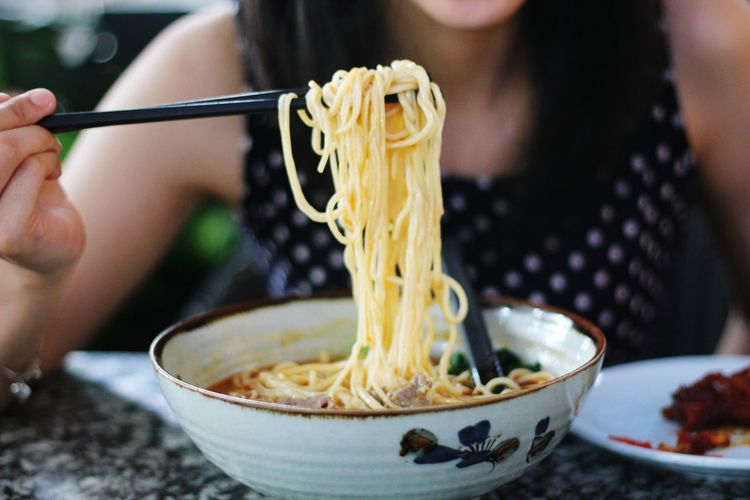 Close-up of woman eating ramen noodles