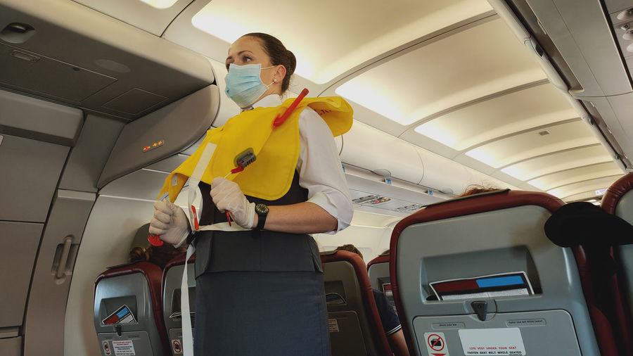 Low angle view of cabin crew wearing mask at airplane