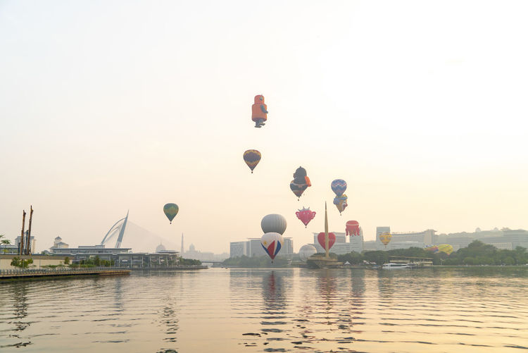 Hot air balloons in lake against clear sky