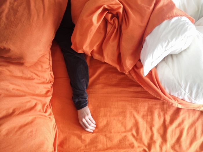 Man's hand on orange bedding