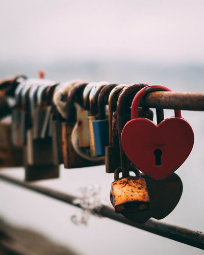 Close-up of padlocks hanging on railing against sky