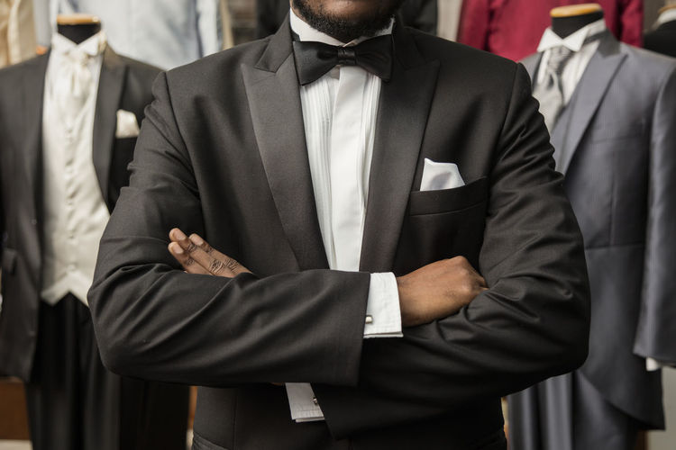 Midsection of man with arms crossed standing at tailor shop